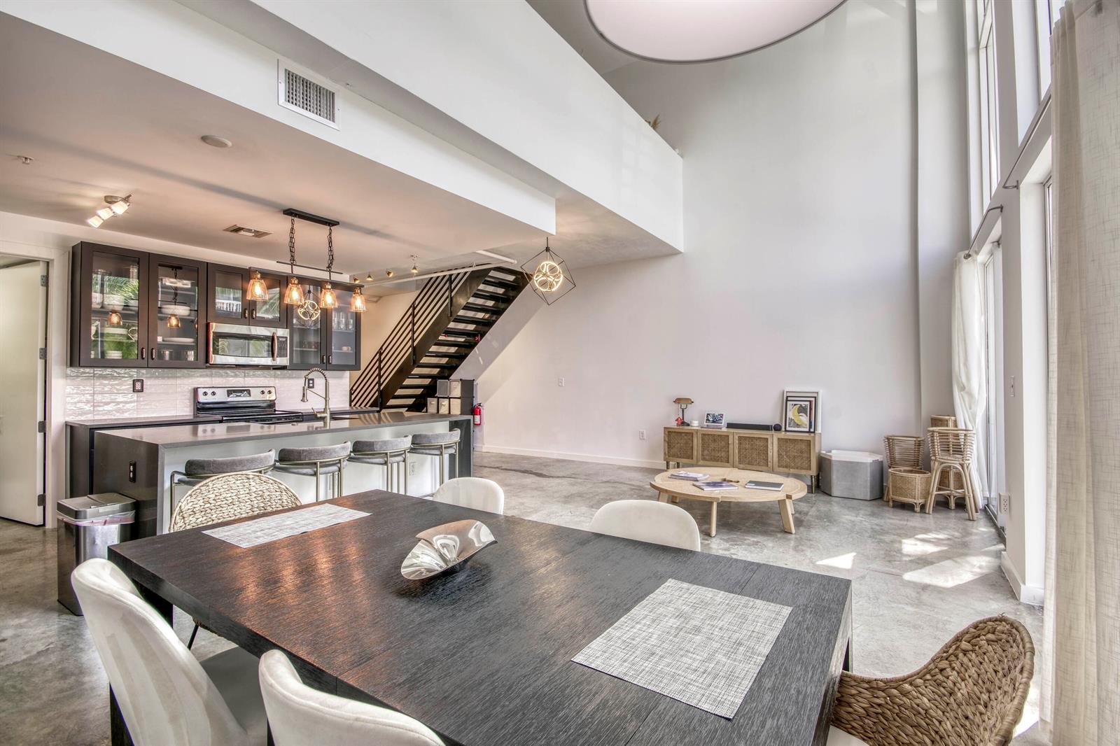 A modern open-concept living area with a kitchen, dining table, and high ceilings — 108 Lake Avenue # 202, FL 33460, FL