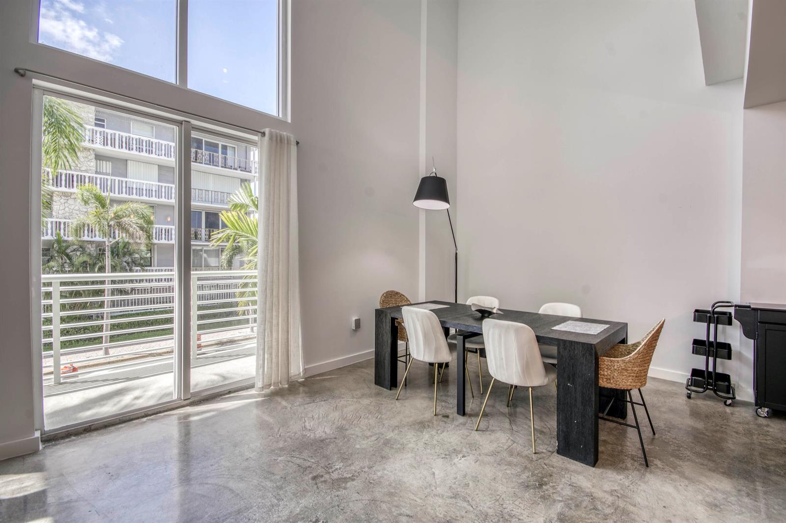 A dining area with a dark table, mixed chairs, and concrete floors near a balcony — 108 Lake Avenue # 202, FL 33460, FL