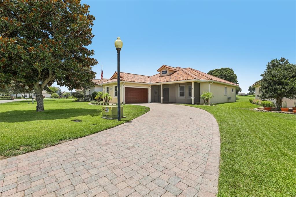 A single-story house with a tile roof and a paved driveway sits on a lawn — 30418 ISLAND CLUB DRIVE, DEER ISLAND, FL
