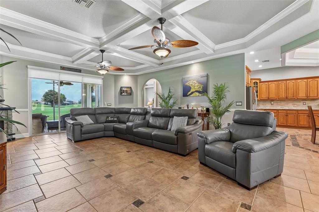 A living room features a grey sectional sofa, tile flooring, and a coffered ceiling — 30418 ISLAND CLUB DRIVE, DEER ISLAND, FL
