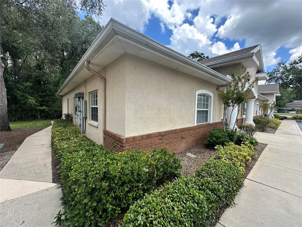 A side view of a beige stucco building with brick accents and surrounding landscaping — 10960 SHELDON ROAD, TAMPA, FL