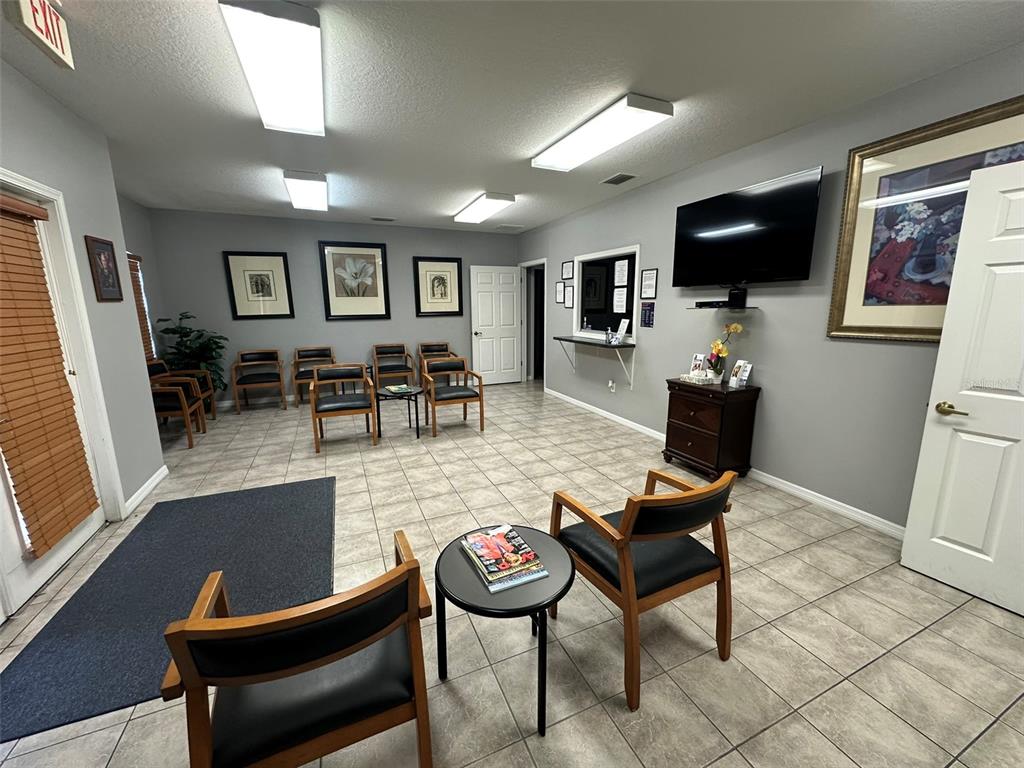 A waiting room features tile flooring, multiple chairs, a television, and framed wall art — 10960 SHELDON ROAD, TAMPA, FL