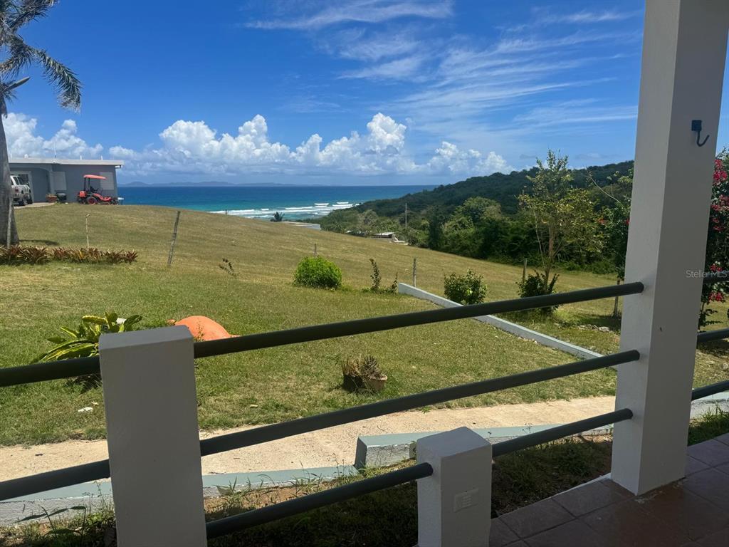 A view of a grassy hill and the ocean from a covered porch with railings — Calle 21, Lote 755, BARRIO SANTA MARIA, VILLA BORINQUEN, VIEQUES, PR