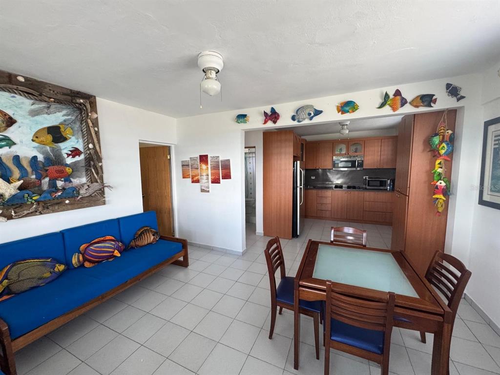 A living room with a blue sofa and dining area leads into an open kitchen — Calle 21, Lote 755, BARRIO SANTA MARIA, VILLA BORINQUEN, VIEQUES, PR