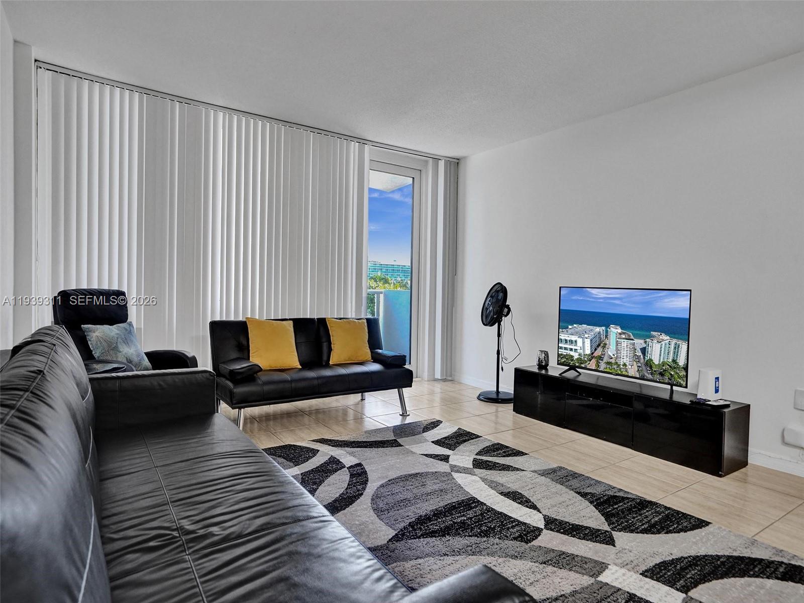 A living room features a black sofa, a patterned rug, and a television on a stand — 3725 S Ocean Dr # 520, Hollywood FL 33019, HOLLYWOOD, FL