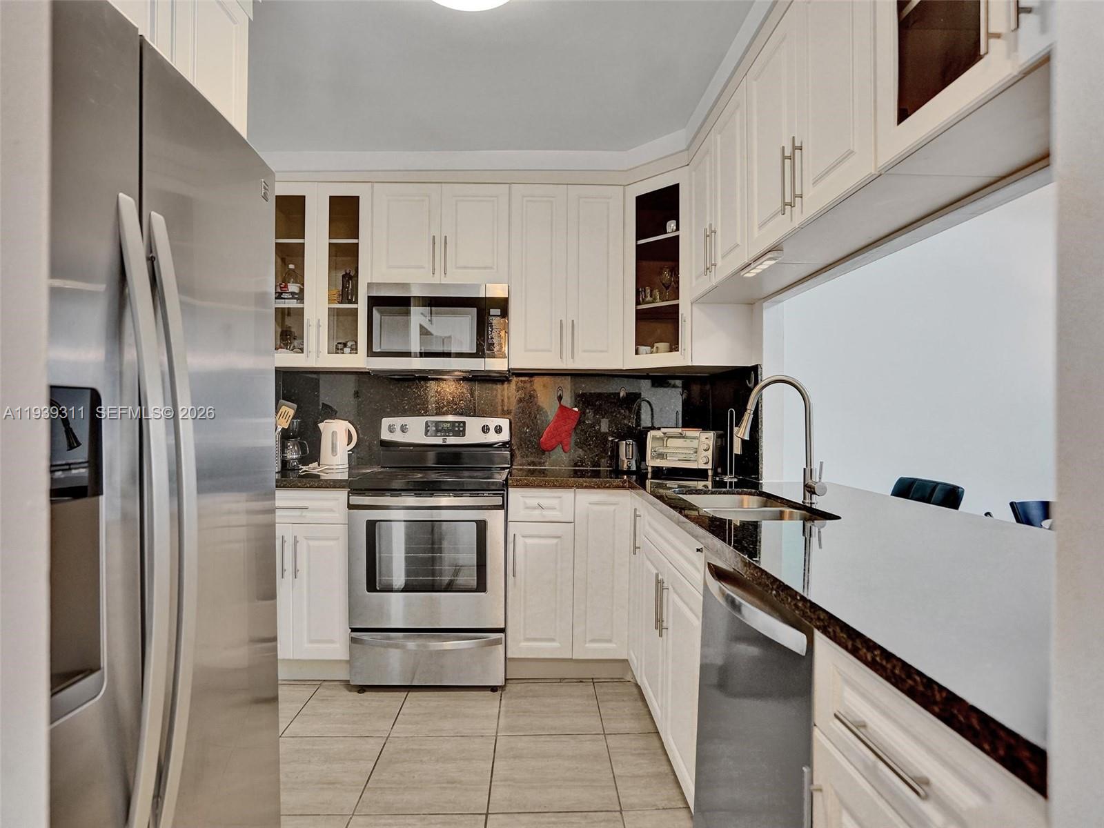 A kitchen features white cabinets, stainless steel appliances, and dark granite countertops — 3725 S Ocean Dr # 520, Hollywood FL 33019, HOLLYWOOD, FL