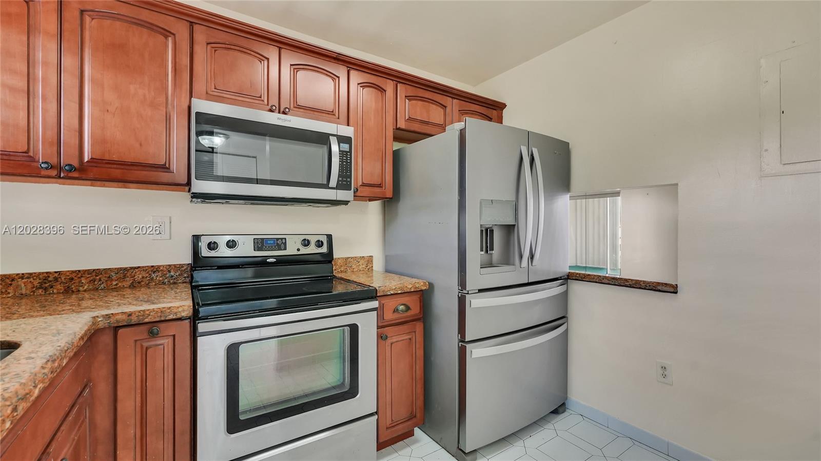 A kitchen features wood cabinets, stainless steel appliances, and granite countertops — 2811 N Pine Island Rd # 302, Sunrise FL 33322, SUNRISE, FL