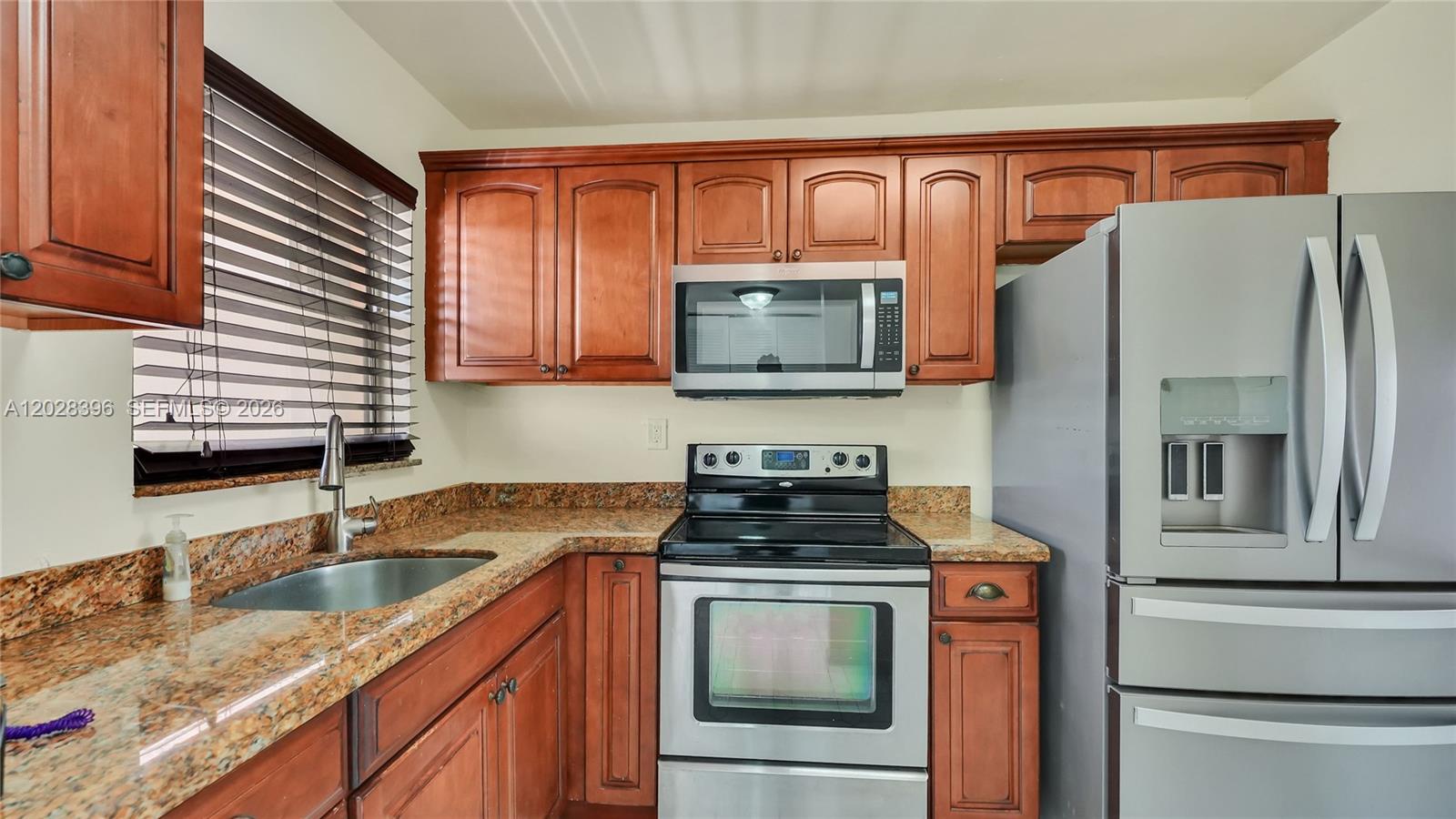 A kitchen features wood cabinets, granite countertops, and stainless steel appliances — 2811 N Pine Island Rd # 302, Sunrise FL 33322, SUNRISE, FL