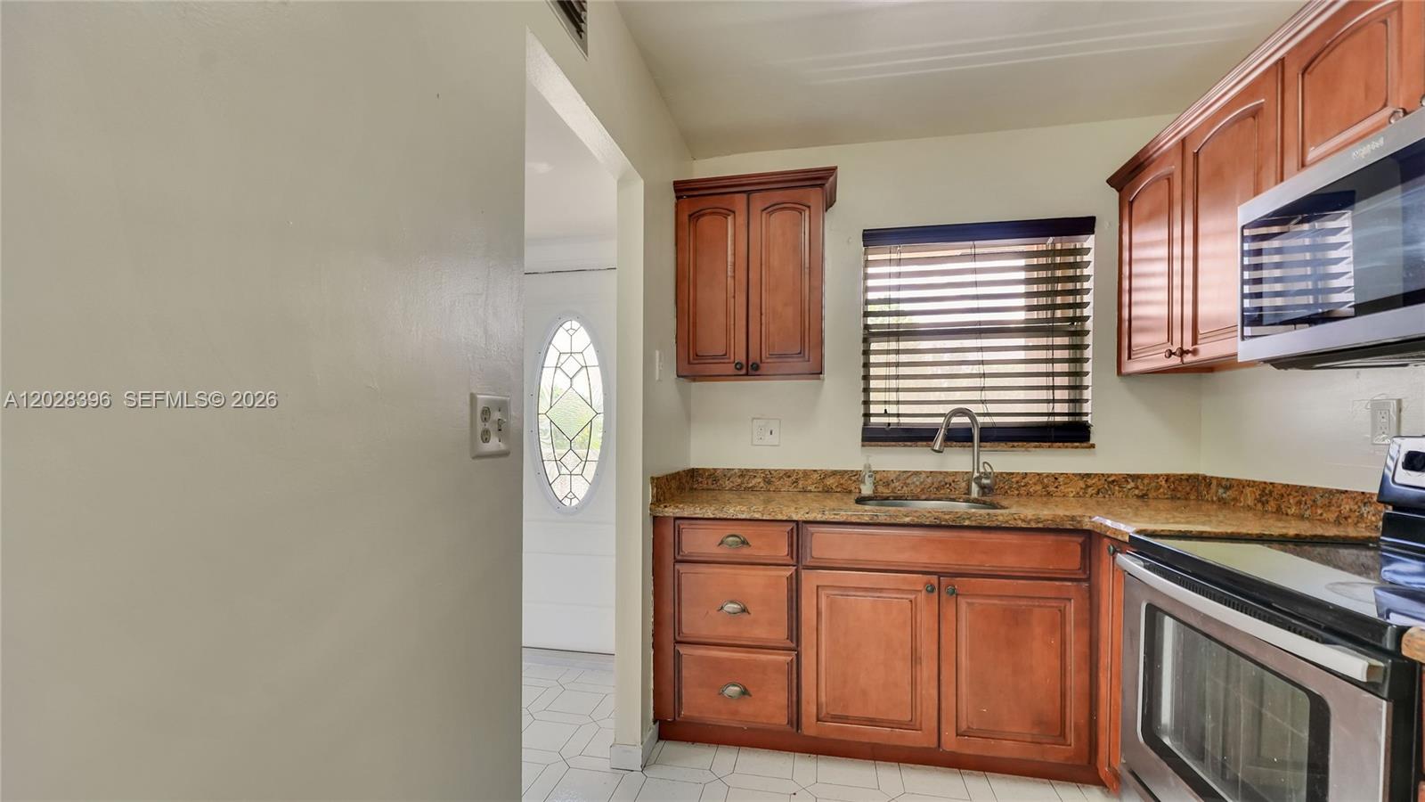 A kitchen features wooden cabinets, granite countertops, a stainless steel oven, and a window — 2811 N Pine Island Rd # 302, Sunrise FL 33322, SUNRISE, FL
