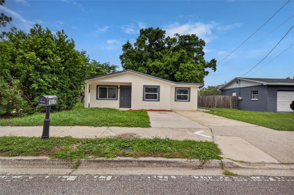 A single-story house with a beige exterior, a concrete driveway, and a mailbox in front — 1610 N LOIS AVENUE, TAMPA, FL