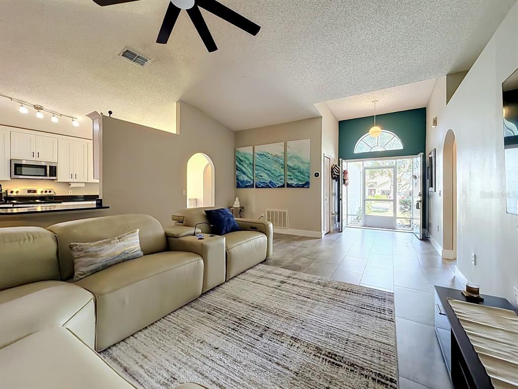 A living room with tile floors, a beige sectional sofa, and an open entryway — 527 DOMINISH ESTATES DRIVE, APOPKA, FL