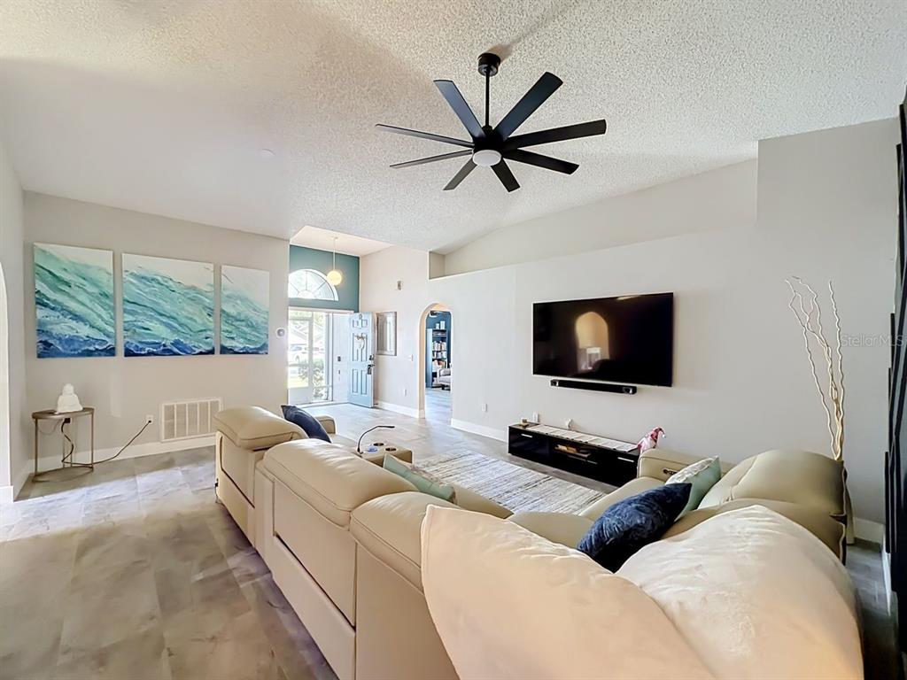 A living room features a large sectional sofa, a wall-mounted television, and a ceiling fan — 527 DOMINISH ESTATES DRIVE, APOPKA, FL