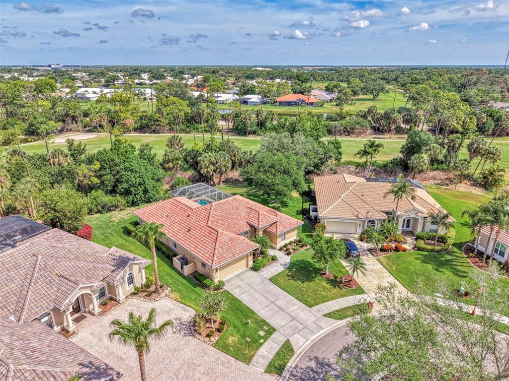 An aerial view shows three suburban houses with tiled roofs and driveways near a golf course — 763 EGRET WALK LANE, VENICE, FL