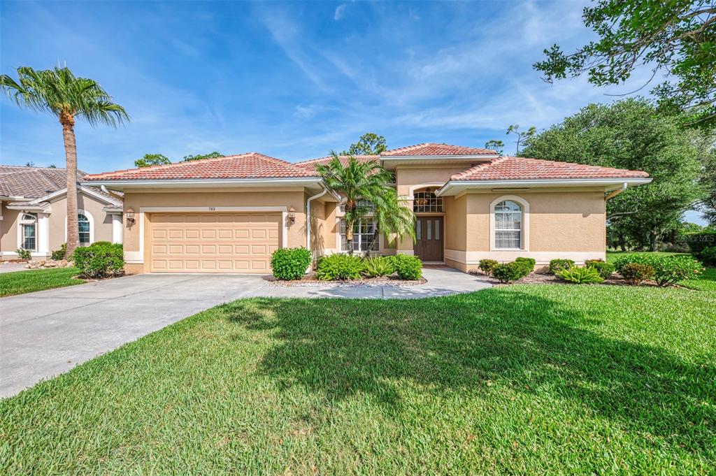 A single-story house with a tile roof, beige stucco exterior, and a two-car garage — 763 EGRET WALK LANE, VENICE, FL