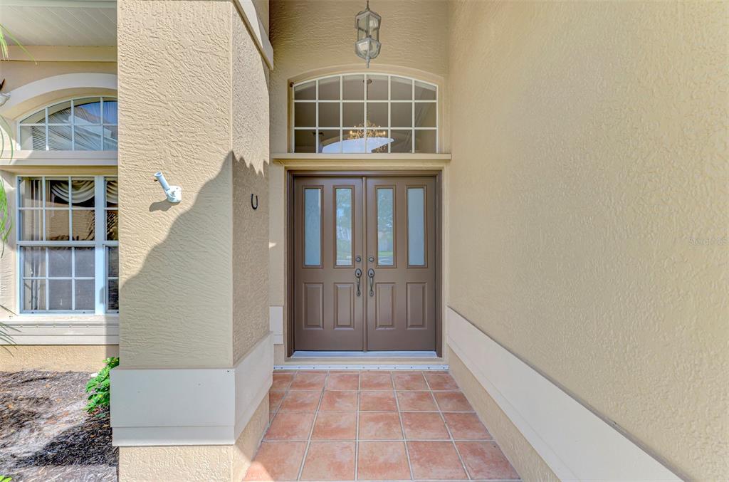 A covered entryway features a double brown door with glass panels and tiled flooring — 763 EGRET WALK LANE, VENICE, FL