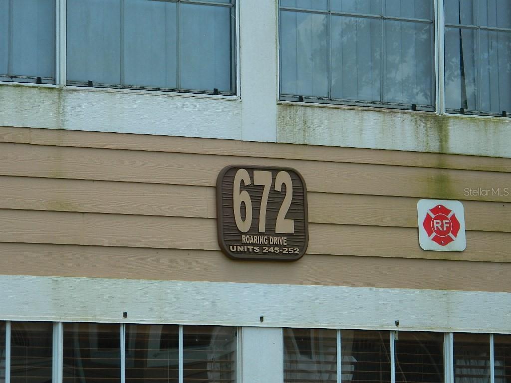 The exterior of a building features a sign displaying the address number 672 — 672 ROARING DRIVE UNIT 245, ALTAMONTE SPRINGS, FL