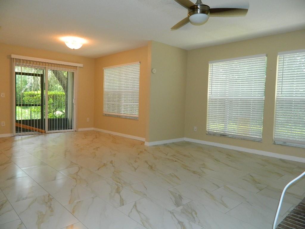 A living room with light-colored marble-look tile flooring, beige walls, and a ceiling fan — 672 ROARING DRIVE UNIT 245, ALTAMONTE SPRINGS, FL