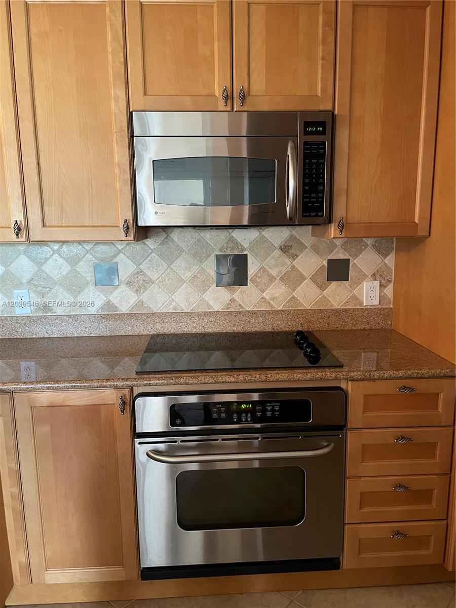 A kitchen features light wood cabinets, stainless steel appliances, and a tiled backsplash — 4408 Renaissance Way # 408, Boynton Beach FL 33426, BOYNTON BEACH, FL