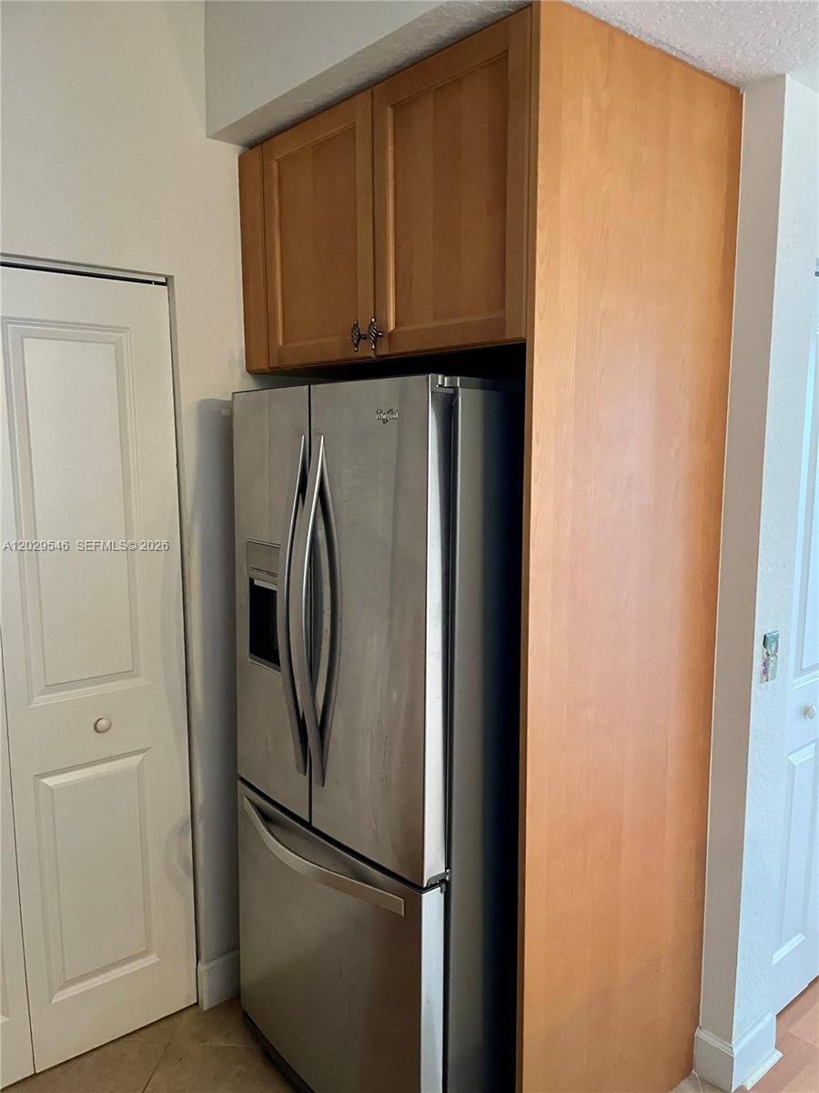A stainless steel refrigerator is built into a wooden cabinet enclosure in a kitchen — 4408 Renaissance Way # 408, Boynton Beach FL 33426, BOYNTON BEACH, FL