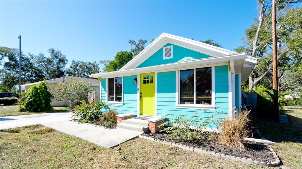 A turquoise house with a bright yellow front door sits on a grassy lot — 522 37TH STREET W, BRADENTON, FL