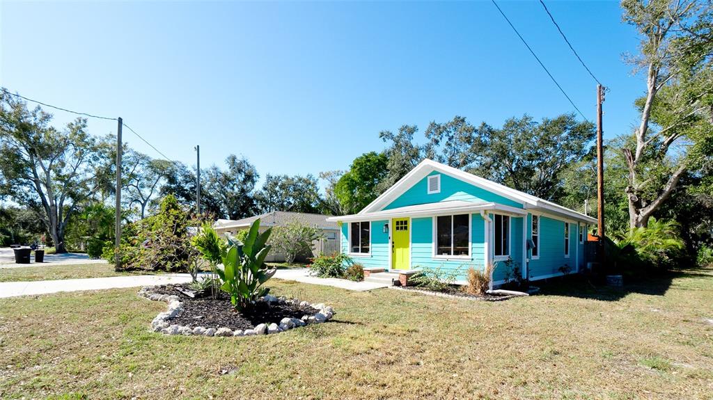 A bright turquoise house with a lime green front door stands on a grassy lot — 522 37TH STREET W, BRADENTON, FL