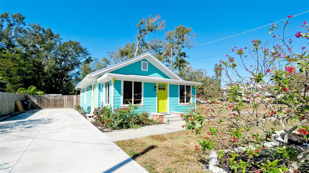 A turquoise house with a bright yellow door sits next to a concrete driveway — 522 37TH STREET W, BRADENTON, FL