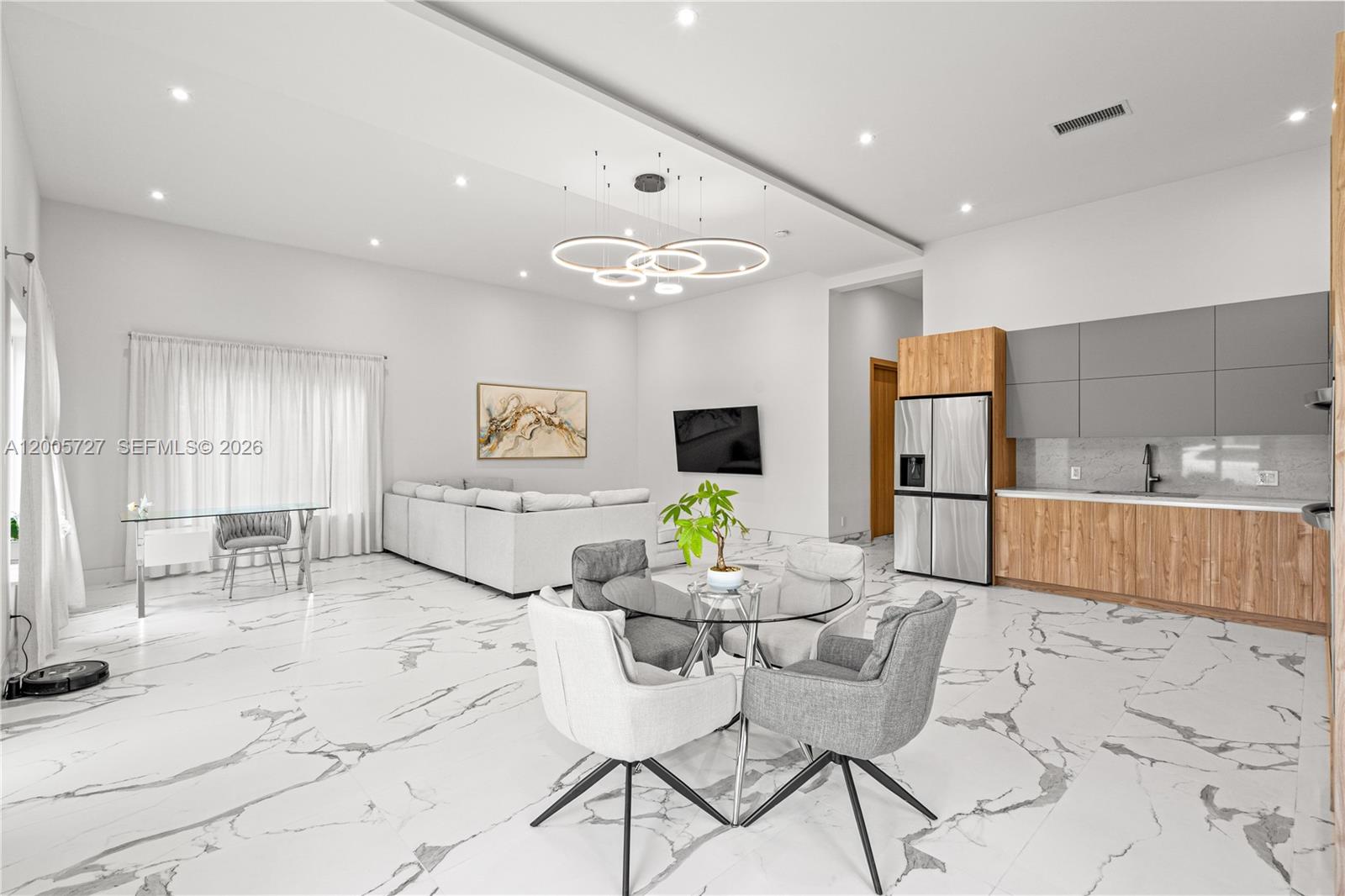 An open-concept living and dining area features white marble flooring and modern kitchen cabinetry — 635 SW 9th St, Hallandale Beach FL 33009, HALLANDALE BEACH, FL