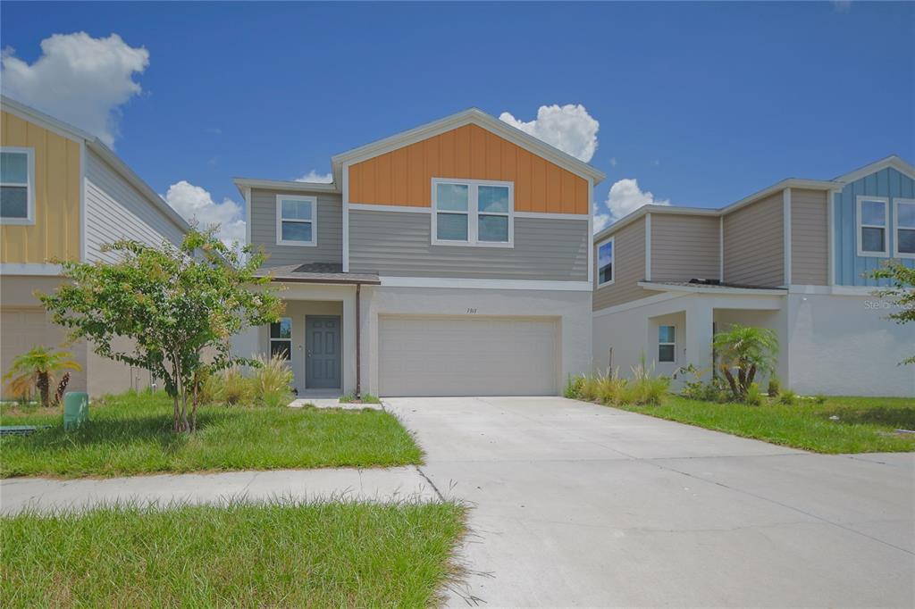 A two-story house with a gray and orange exterior, a two-car garage, and a driveway — 7917 PEACE LILY AVENUE, WESLEY CHAPEL, FL