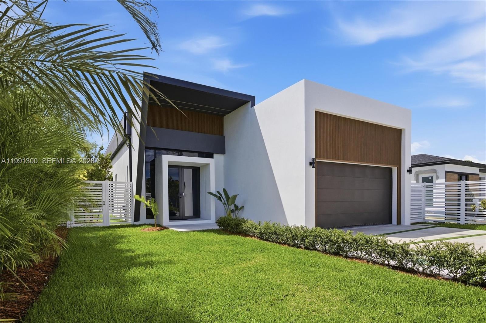 A modern single-story house features a white facade, wood-slat accents, and a dark garage door — 22900 SW 122 PL, Miami FL 33170, MIAMI, FL