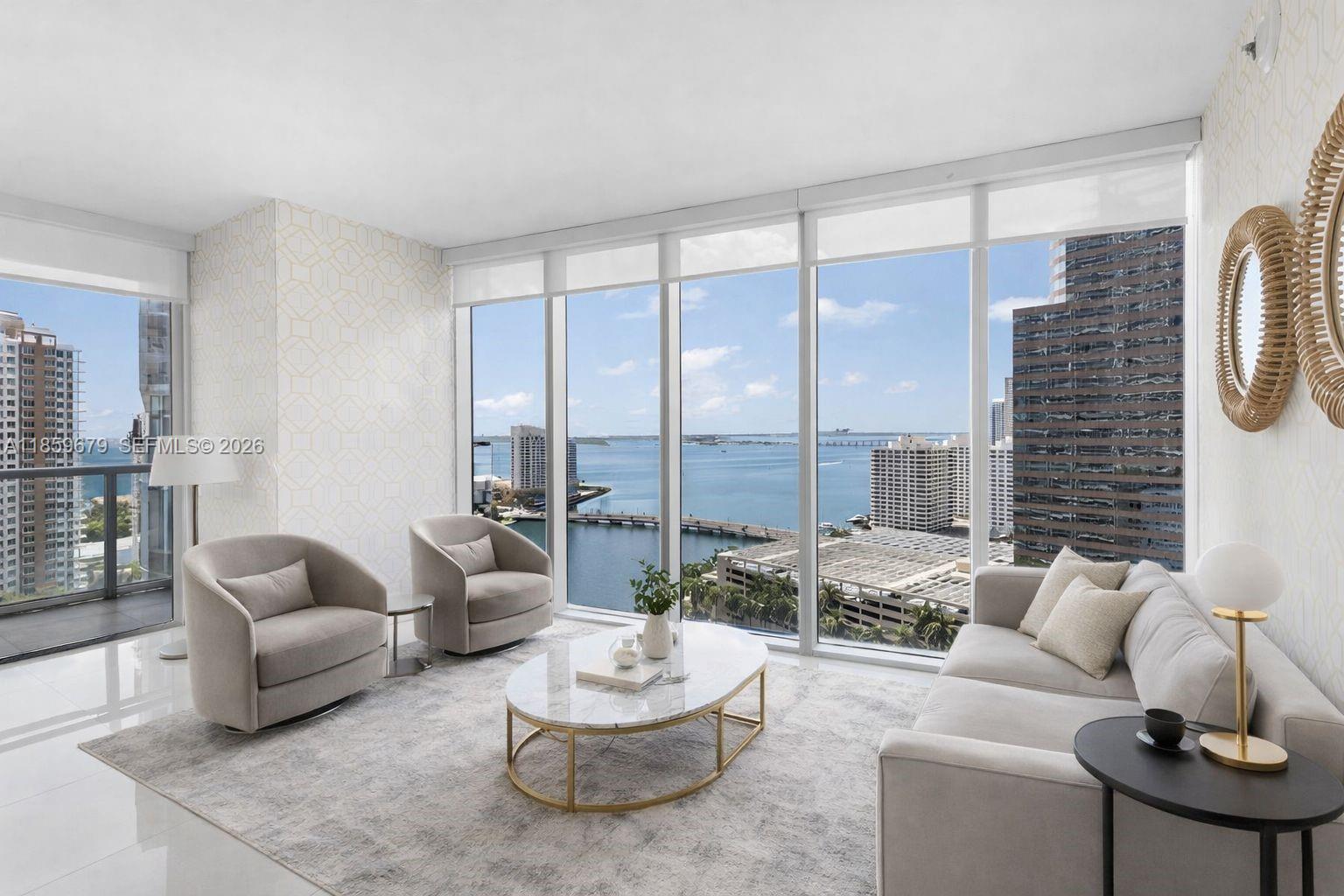 A modern living room features floor-to-ceiling windows with a panoramic view of the bay — 485 Brickell Ave # 2210, Miami FL 33131, MIAMI, FL
