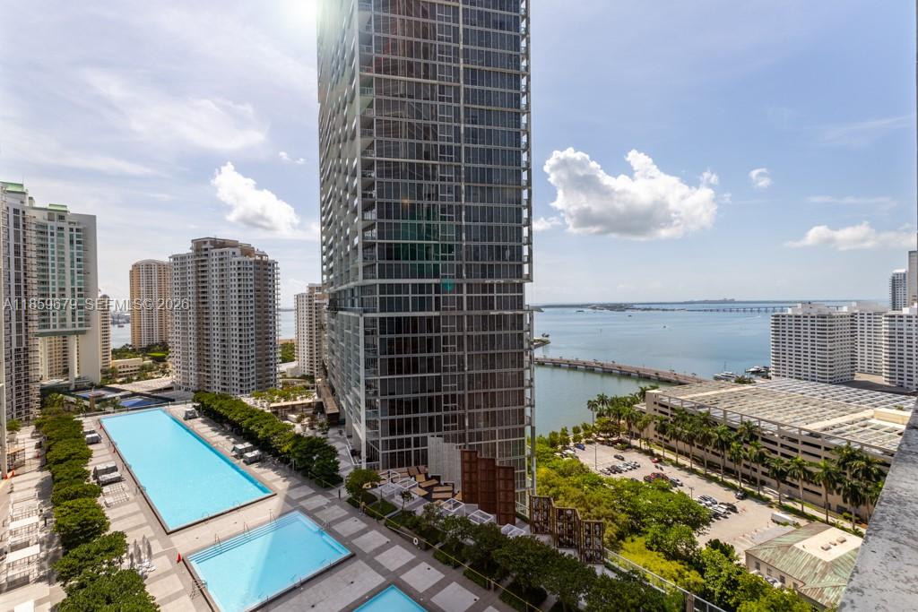 An elevated view of a high-rise building, swimming pools, and a bay with a bridge — 485 Brickell Ave # 2210, Miami FL 33131, MIAMI, FL