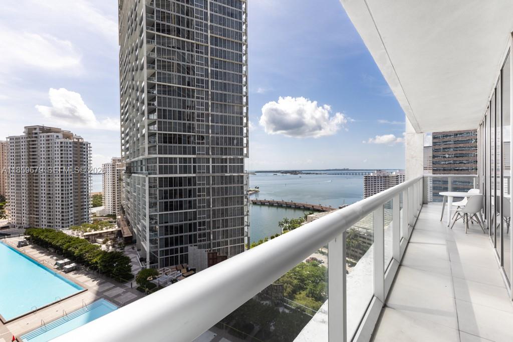 A high-rise balcony overlooks a swimming pool, nearby skyscrapers, and a bay with a bridge — 485 Brickell Ave # 2210, Miami FL 33131, MIAMI, FL