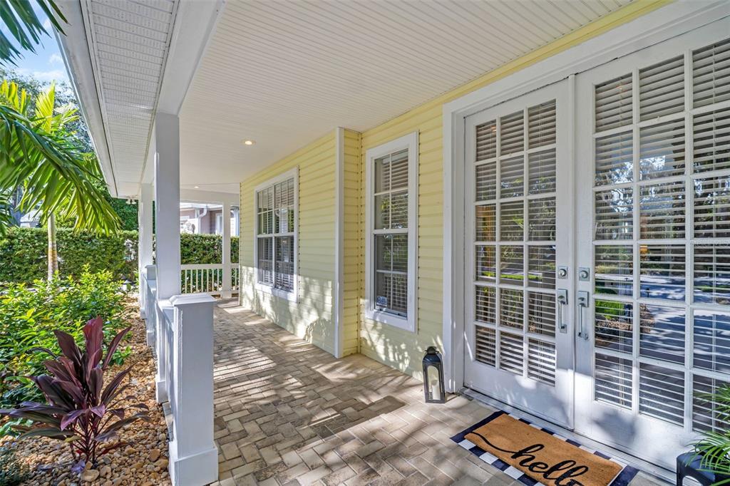A covered porch with yellow siding, brick pavers, and double glass doors with white frames — 266 FLORIDA BOULEVARD, CRYSTAL BEACH, FL