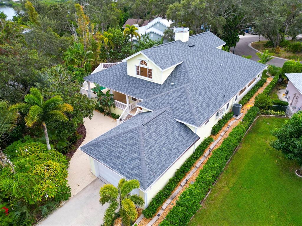 An aerial view shows a yellow house with a gray shingled roof and landscaping — 266 FLORIDA BOULEVARD, CRYSTAL BEACH, FL