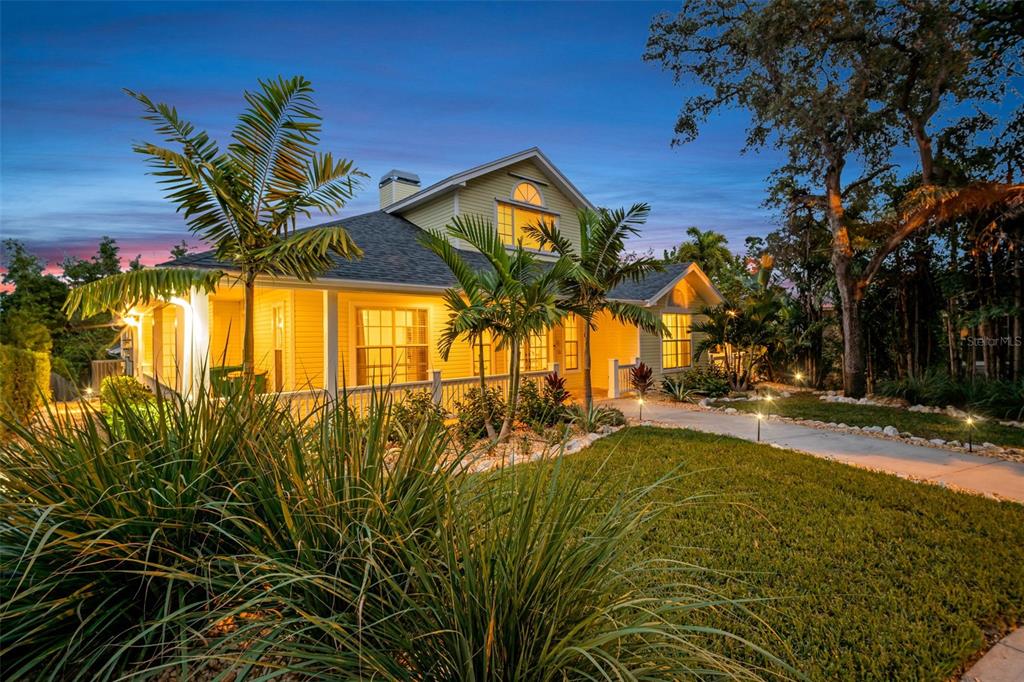 A yellow two-story house with a wrap-around porch and palm trees at dusk — 266 FLORIDA BOULEVARD, CRYSTAL BEACH, FL