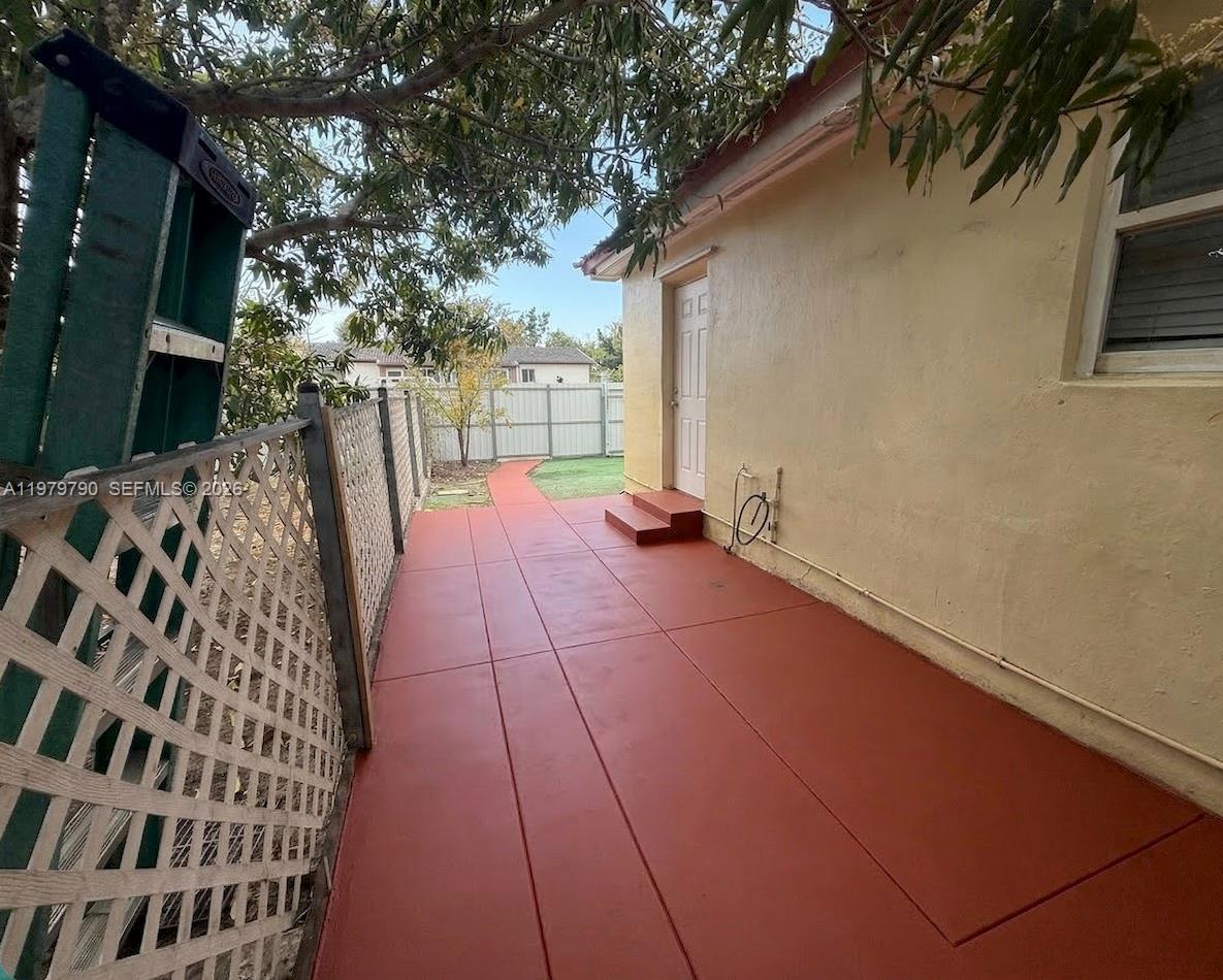 A side yard features a red-painted concrete patio, a white door, and a lattice fence — 20221 SW 112th Ct # 2, Miami FL 33189, MIAMI, FL