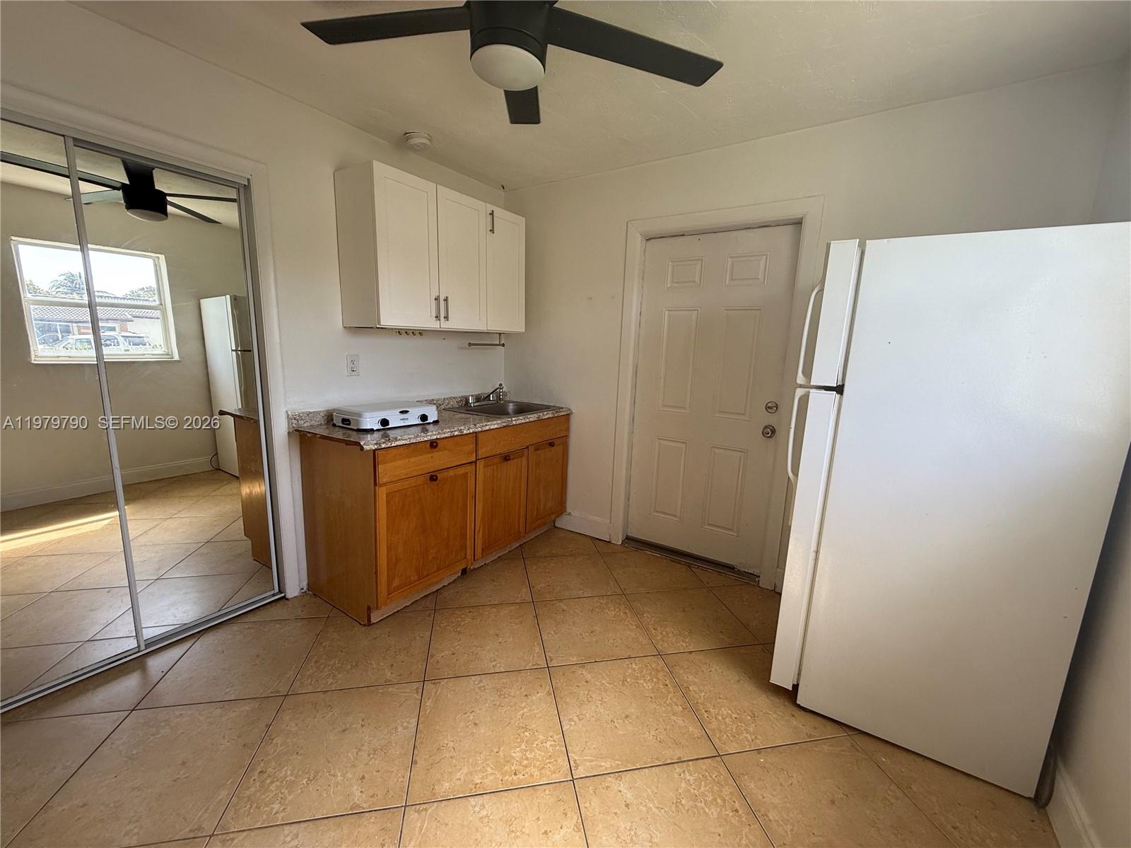 A small kitchen features wooden cabinets, a portable stove, a sink, and a white refrigerator — 20221 SW 112th Ct # 2, Miami FL 33189, MIAMI, FL