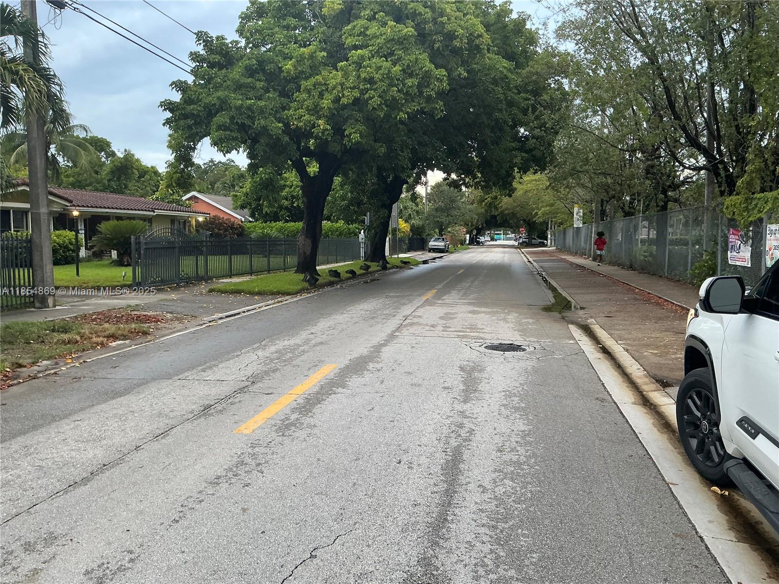 A residential street view shows a paved road lined with trees, fences, and parked cars — 1855 NW 32nd St, Miami FL 33142, MIAMI, FL