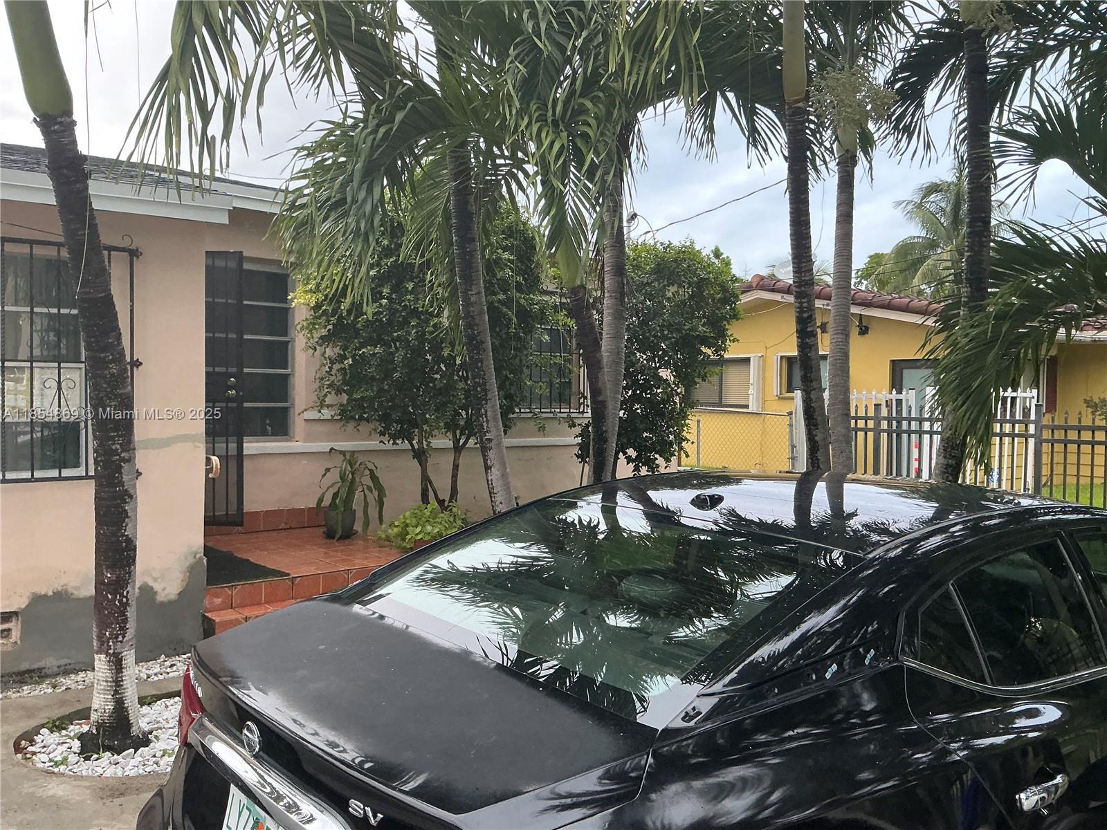 A black sedan is parked in front of a house with palm trees and landscaping — 1855 NW 32nd St, Miami FL 33142, MIAMI, FL