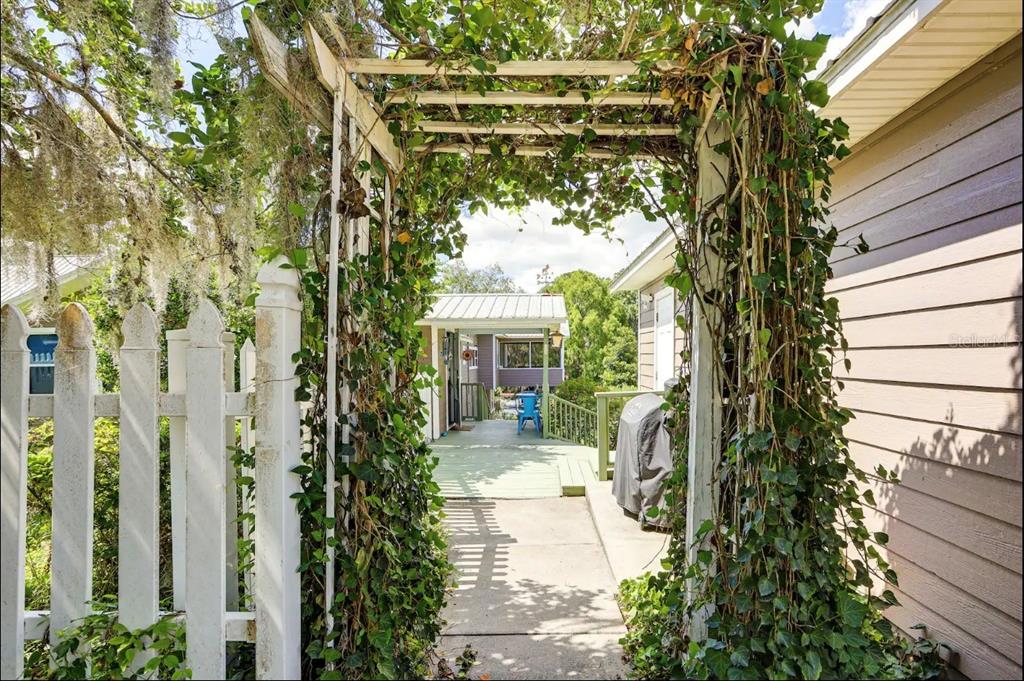 A white wooden arbor covered in ivy stands over a walkway leading to a deck — 20906 RIVER DRIVE, DUNNELLON, FL