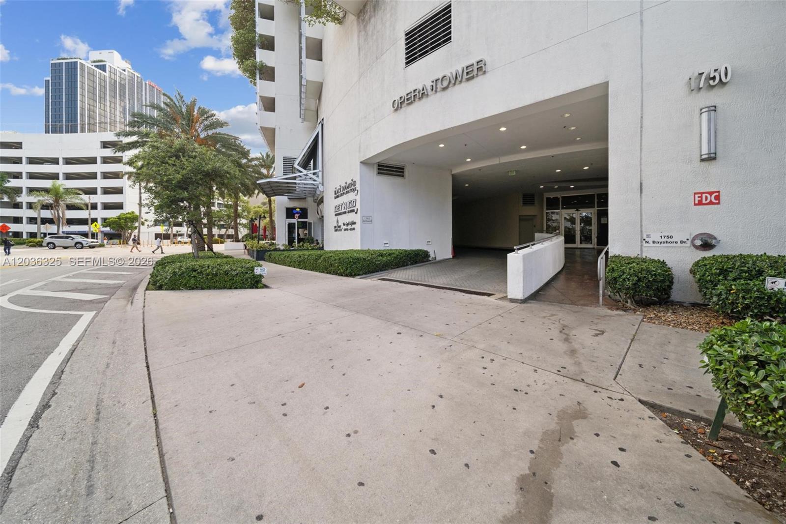 The exterior of the Opera Tower building features a covered driveway entrance and landscaped bushes — 1750 N Bayshore Dr # 4315, Miami FL 33132, MIAMI, FL