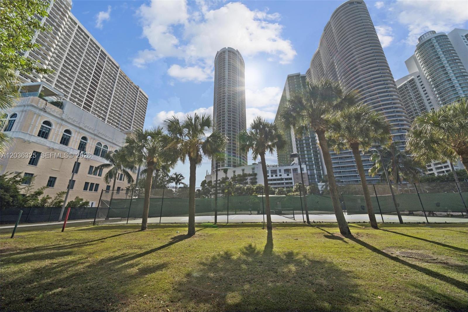 A tennis court sits in front of several tall residential skyscrapers under a sunny sky — 1750 N Bayshore Dr # 4315, Miami FL 33132, MIAMI, FL