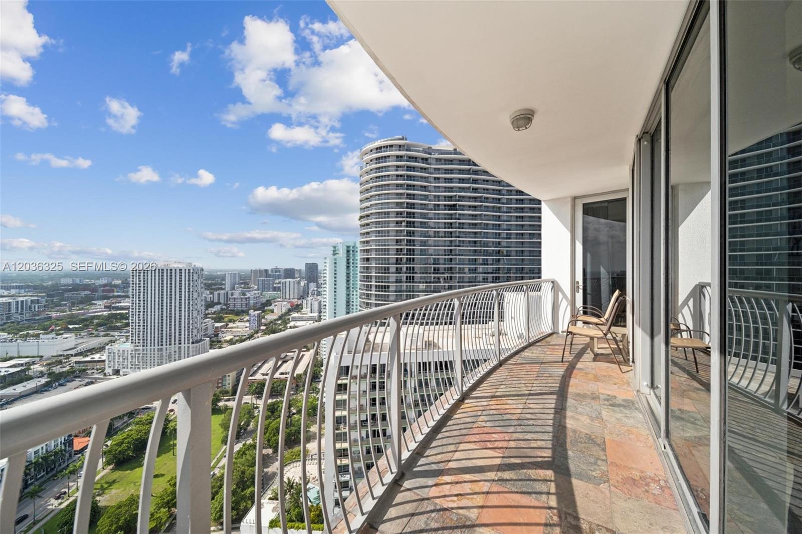 A high-rise balcony features a tiled floor, metal railing, and views of surrounding city buildings — 1750 N Bayshore Dr # 4315, Miami FL 33132, MIAMI, FL