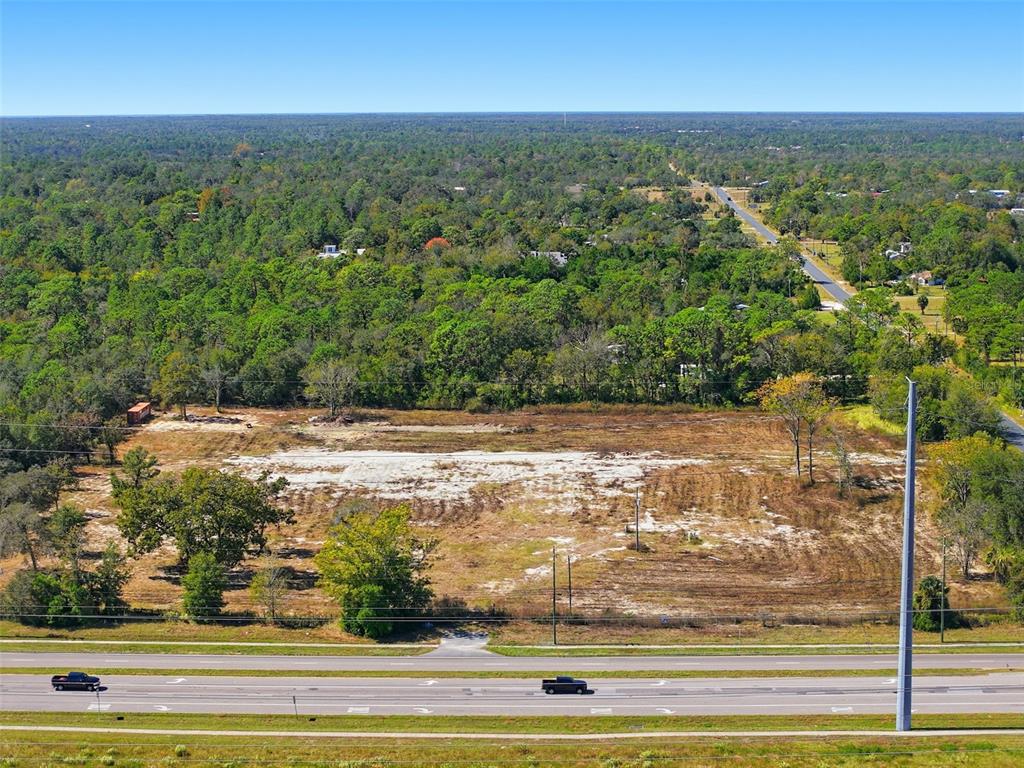 An aerial view shows a cleared, rectangular lot of land adjacent to a multi-lane highway — 9247 SUNSHINE GROVE ROAD, BROOKSVILLE, FL