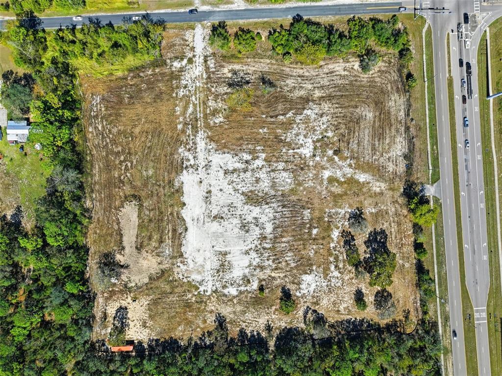 An aerial view shows a cleared, rectangular plot of land bordered by trees and roads — 9247 SUNSHINE GROVE ROAD, BROOKSVILLE, FL