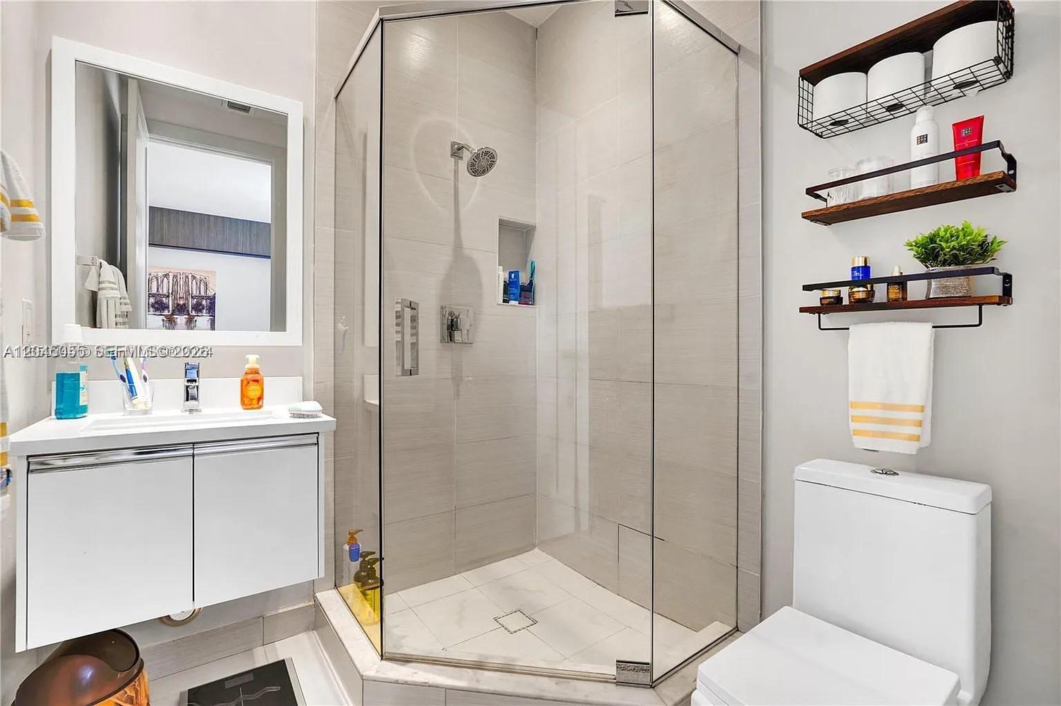 A modern bathroom features a glass-enclosed corner shower, a white vanity, and wall-mounted shelving — 6319 NW 105 CT # 0, Doral FL 33178, DORAL, FL