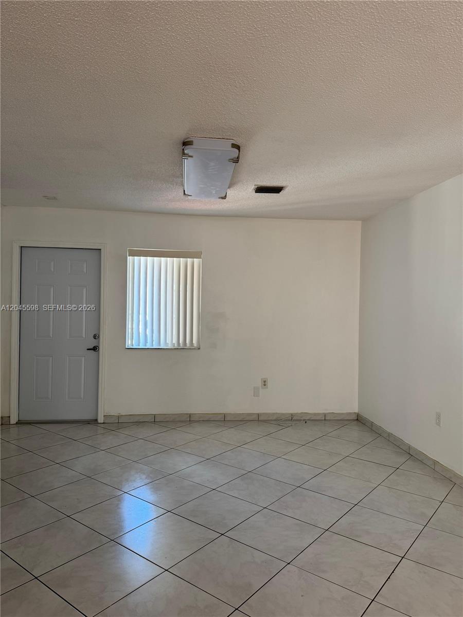 A room with white walls, tiled floors, a single window with blinds, and a door — 13907 SW 177th St # 13907, Miami FL 33177, MIAMI, FL