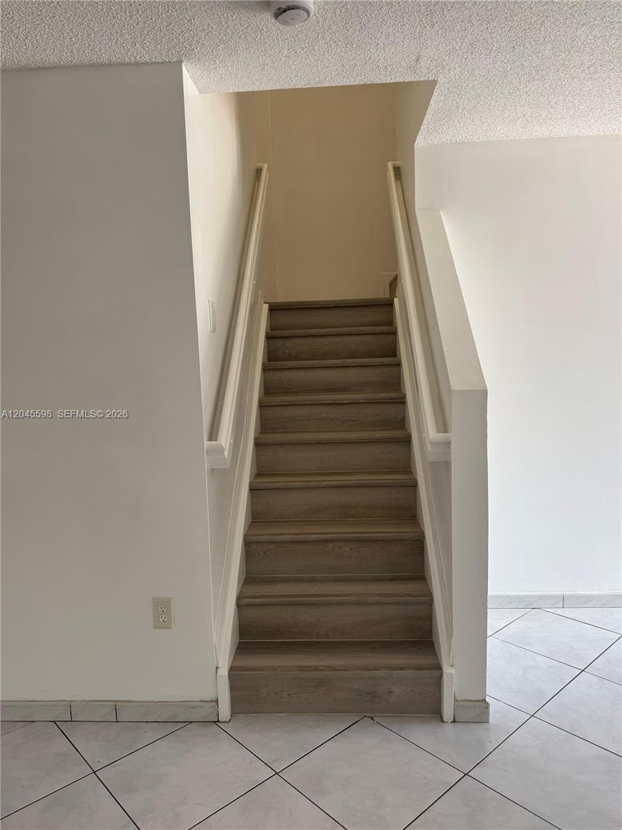 A staircase with wood-look treads leads upward between two white walls — 13907 SW 177th St # 13907, Miami FL 33177, MIAMI, FL