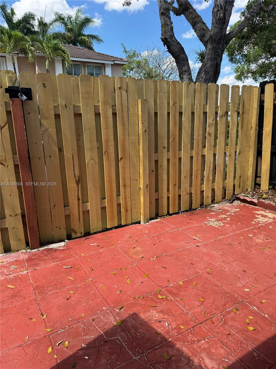A wooden fence encloses a patio area with red patterned concrete pavers — 13907 SW 177th St # 13907, Miami FL 33177, MIAMI, FL