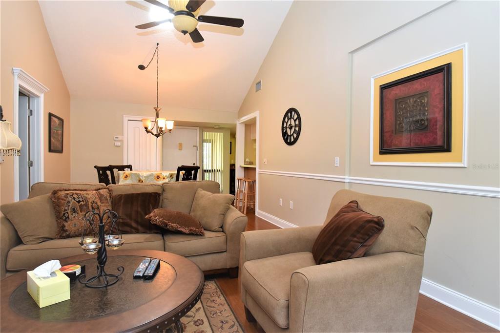 A living room features tan walls, a vaulted ceiling, a ceiling fan, and beige furniture — 1637 BROOKHOUSE COURT UNIT BR243, SARASOTA, FL